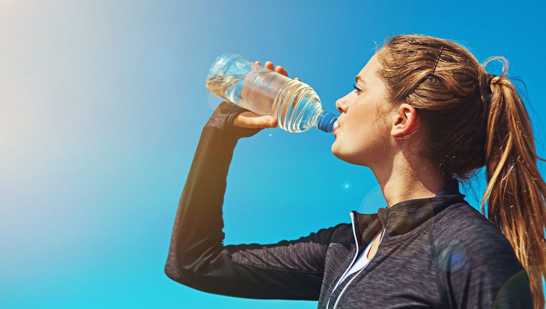 Woman with ponytail drinking from water bottle